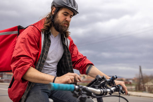 istock Male delivery person, using mobile phone, while riding bicycle 1404664075