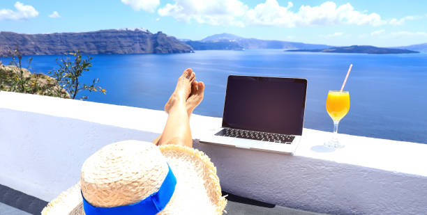 istock Computer laptop and orange juice which  woman freelancer with running remotely with bright scenic view of the Mediterranean Sea and Santorini caldera -work vacation concept 1404666348
