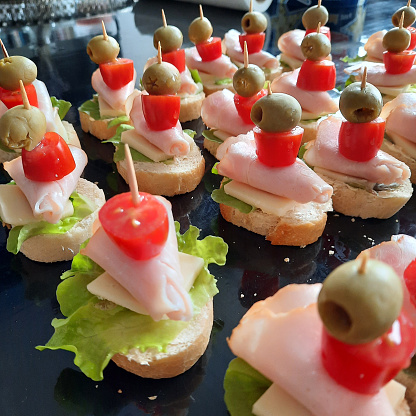 The table is laden with canapes and mini sandwiches with olives and ham.