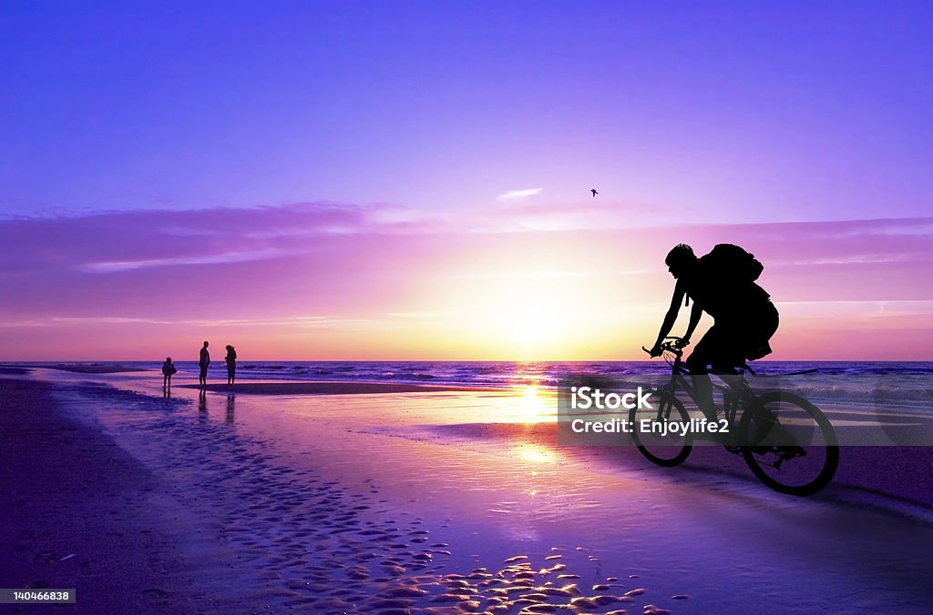 mountain biker on beach and sunset silhouette of a mountain biker on beach and sunset Beach Stock Photo