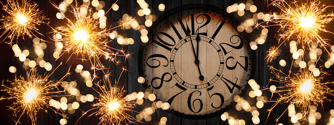HAPPY NEW YEAR 2023 - Festive silvester New Year's Eve Party celebration background panorama banner long - Golden yellow fireworks, sparklers and clock on rustic black wooden wall texture in the night
