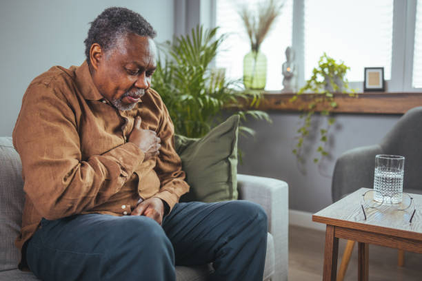 Upset older man touching chest Upset older man touching chest, talking on phone, unhappy mature male having heart attack, lonely grandfather suffering from heartache disease at home, feeling pain, sitting alone. male chest pain stock pictures, royalty-free photos & images