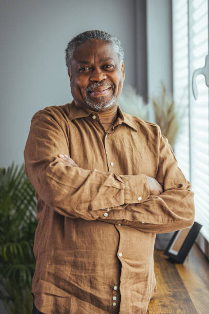 Portrait of an older man wearing a shirt on a gray background. Portrait of an older man wearing a shirt on a gray background. A happy old man looks at a camera isolated over a gray wall. An older man smiles at the camera, a happy old man. black man stock pictures, royalty-free photos & images