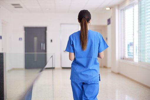 A nurse walks down the corridor in a hospital.