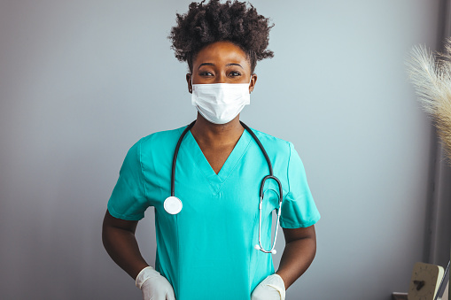 Portrait of a confident doctor working at a hospital. Portrait of a young nurse/doctor. Portrait of female African American doctor standing in her office at clinic. Woman hospital worker looking at camera and smiling