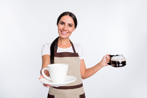 Photo of optimistic nice brown hair lady give cup wear t-shirt apron isolated on grey color background.