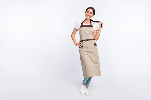 Full length portrait of a young woman in red apron with hands on hips. Vertical shot. Isolated on white.