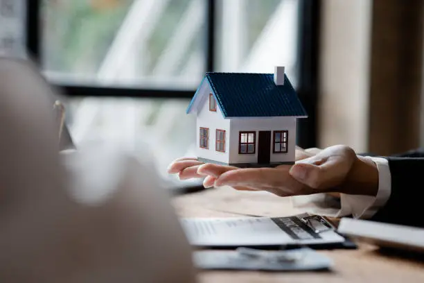 Real estate agents are carrying a housing model of the project to be forwarded to customers as home delivery. Real estate trading ideas and bank loans for buying and selling houses and land.