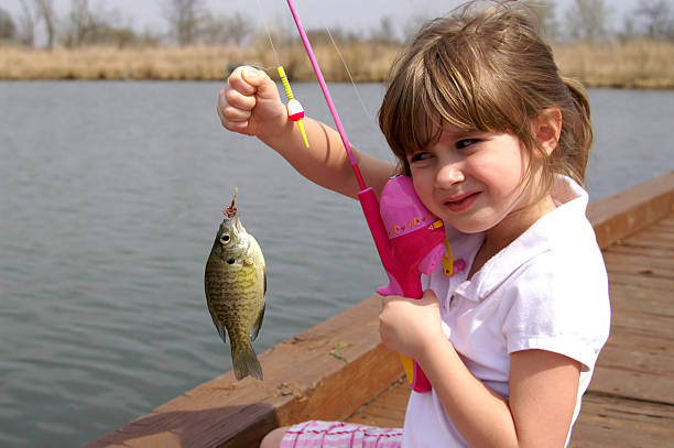 A little girl caught a fish on a wooden boat A young girl holding the fish she caught fishing worm stock pictures, royalty-free photos & images