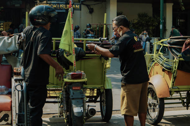 Two Pedicab Drivers Yogyakarta, Indonesia, May 2022  - Two pedicab drivers having a discussion on the side of the road no rickshaws sign stock pictures, royalty-free photos & images