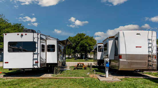 Rv motorhome and fifth wheel trailer parked side by side at campsites