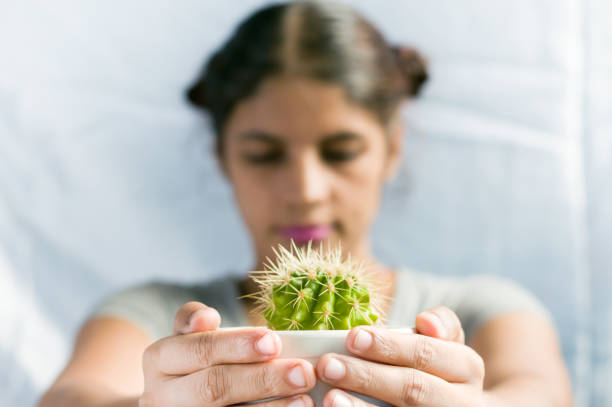 Beautiful young woman holding cactus plant in a ceramic pot, Environment day concept.