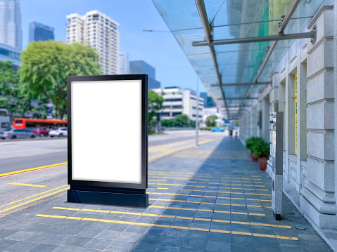 Blank vertical advertising poster banner mockup at bus stop shelter by main road, at city centre; out-of-home OOH billboard media display space. clarke quay area