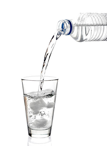 グラスに注がれるミネラルウォーターとグラス - overflowing water glass bottle ストックフォトと画像