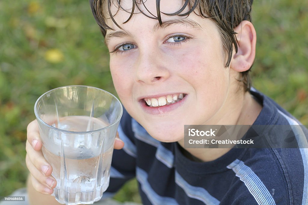 Garçon boire un verre d'eau sourire - Photo de Adolescence libre de droits