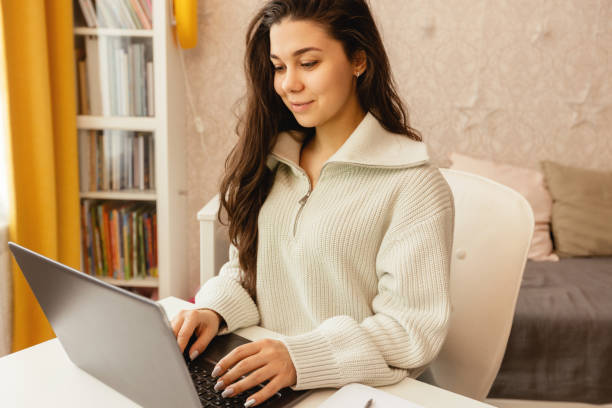 istock A girl works at home at a table with a laptop. 1404690516