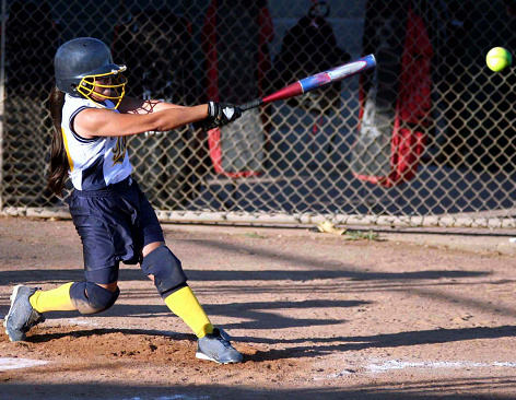 Powerful fastpitch softball swing, with ball flying off the bat.