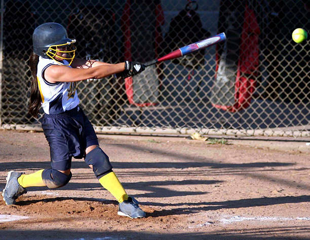Swinging with power Powerful fastpitch softball swing, with ball flying off the bat. baseball hitter stock pictures, royalty-free photos & images
