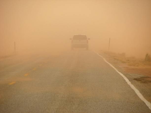 sandstorm driving driving along a highway into an orange sandstorm in Northern Arizona, visibility is reduced drastically dust storm stock pictures, royalty-free photos & images