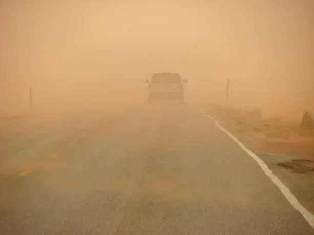 driving along a highway into an orange sandstorm in Northern Arizona, visibility is reduced drastically