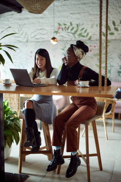istock Two multicultural female students sitting in cafeteria and study for exam. 1404693075