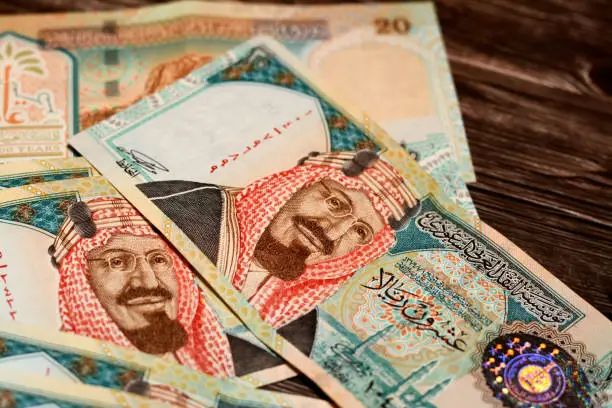 Saudi Arabia 20 SAR twenty Saudi riyals cash money banknote with the photo of king AbdulAziz Al Saud, Quba mosque in Madinah and mountain of light isolated on a wooden background, selective focus
