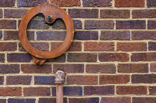 istock Background close up of a brick wall with pipe and iron circle attached 1404695492
