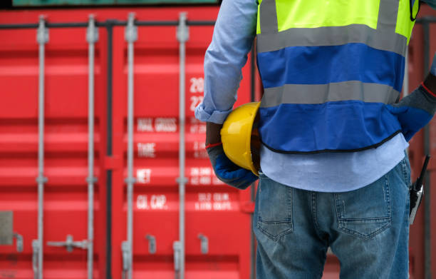 istock Close up engineer hand hold safety yellow helmet with container background. 1404695979