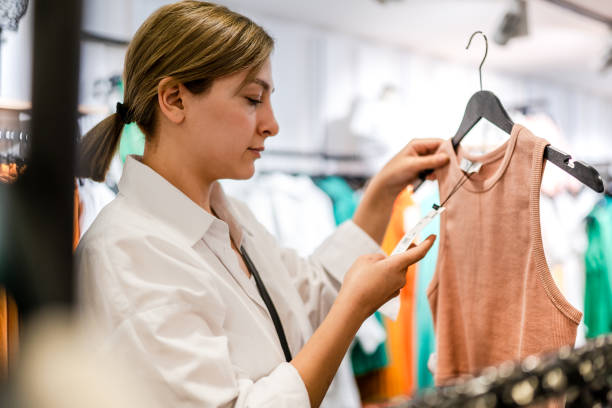 Young woman looking at price tag while shopping stock photo