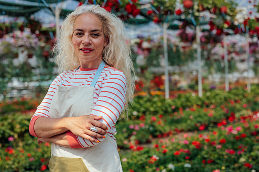 Portrait of middle age woman with folded arms standing in garden center