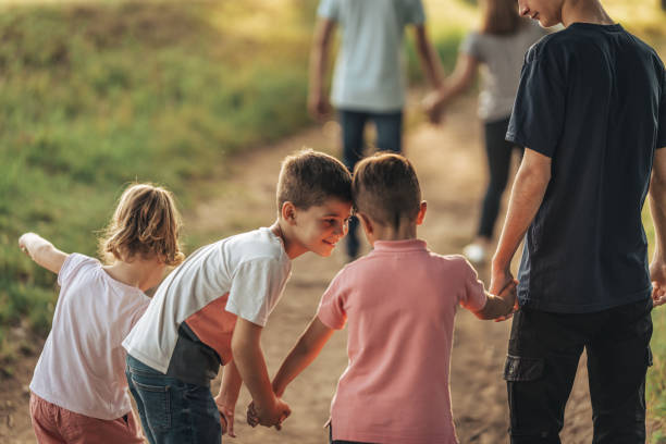 Family of six, three boys and a little girl taking a walk  with their mother and father together in nature.