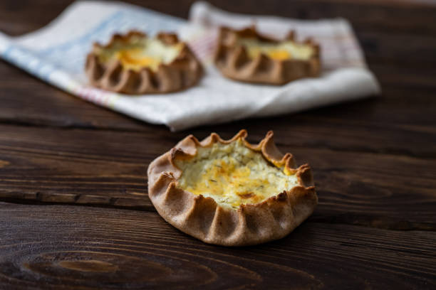 Karelian rye pie Karelian rye pie with soft cheese (originally there should be potatoes) on dark wooden background republic of karelia russia stock pictures, royalty-free photos & images