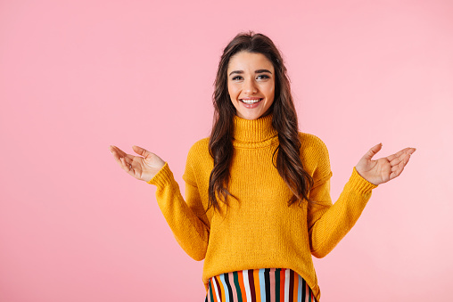 Beautiful young woman wearing colorful clothes standing isolated over pink background