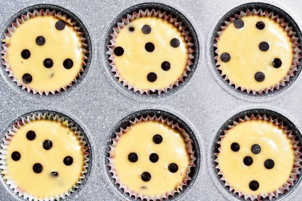 istock Baking tray with muffins paper cases filled with muffin dough, ready for baking 1404700548