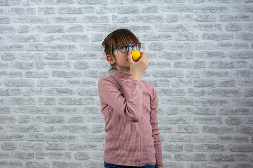 Anosmia or smell blindness, loss of the ability to smell, one of the possible symptoms of covid-19, infectious disease caused by corona virus. Girl children Trying to Sense Smell of a Lemon, side view