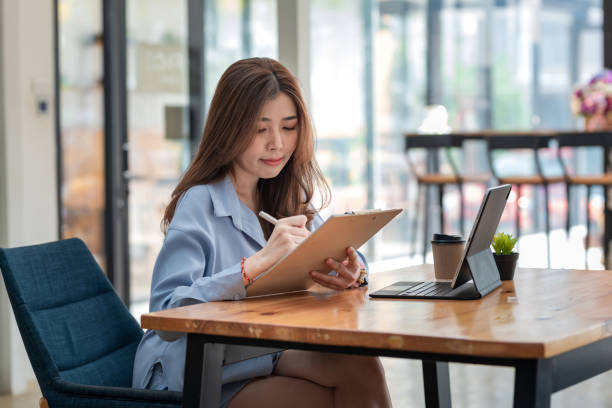 istock Charming businesswoman sitting and taking notes with a tablet at the office. 1404710028