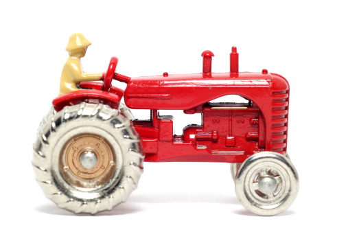Picture of a old small toy Massey Harris Tractor. British metal toy from my brothers toy collection. Replica from a 1950's toy made in 1988.(so too not that young) Isolated on real white.