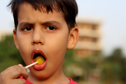 Cute elementary age child eating lollipop portrait outdoor in nature.