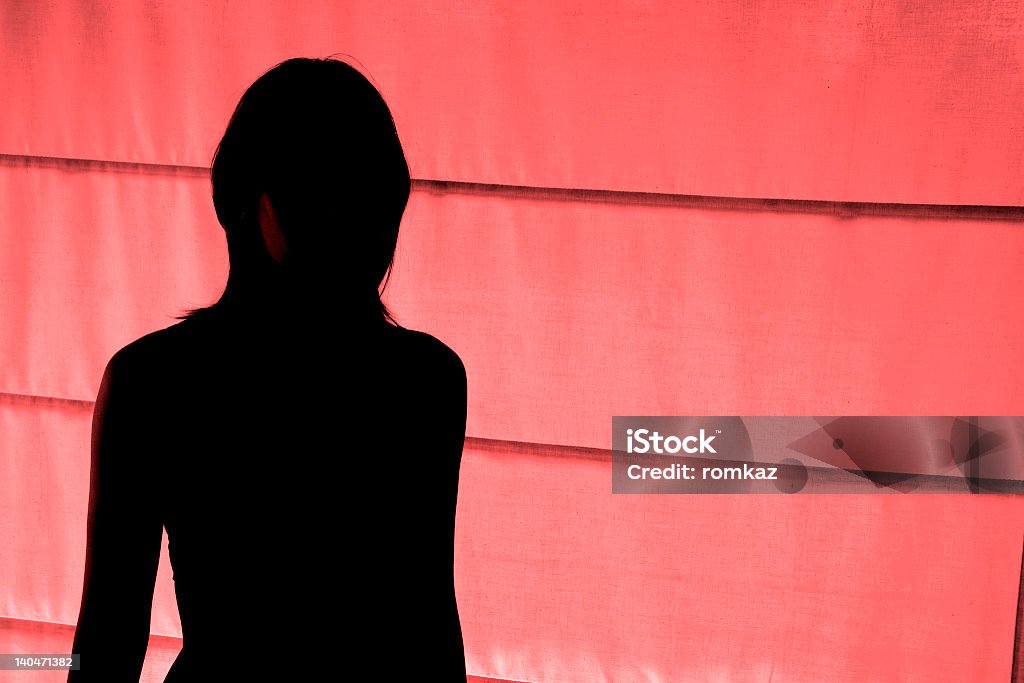 Silhouetted view of woman standing at red light district Woman working in sex industry Prostitute Stock Photo