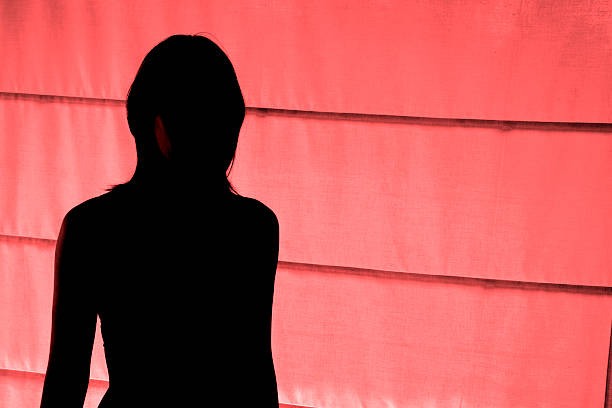 Silhouetted view of woman standing at red light district stock photo