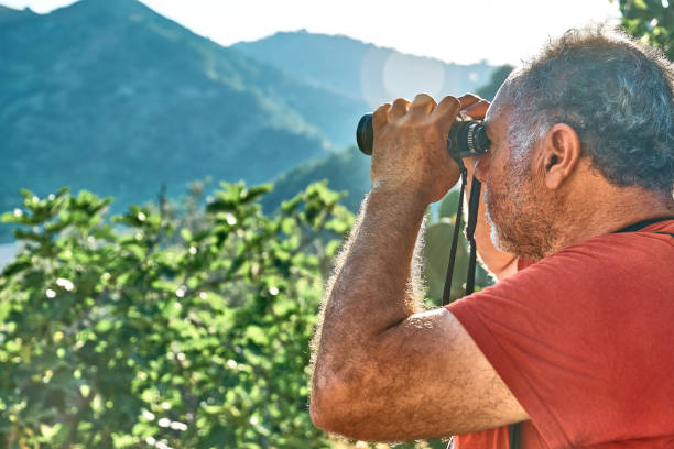 istock Tourist man looking through binoculars at the mountains view. Traveling with backpack or exercising outdoors. Active people, hiking, healthy lifestyle and harmony concept. Unity with nature. 1404716058