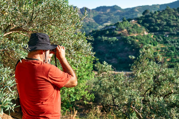 istock Tourist man looking through binoculars at the mountains view. Traveling with backpack or exercising outdoors. Active people, hiking, healthy lifestyle and harmony concept. Unity with nature. 1404716607