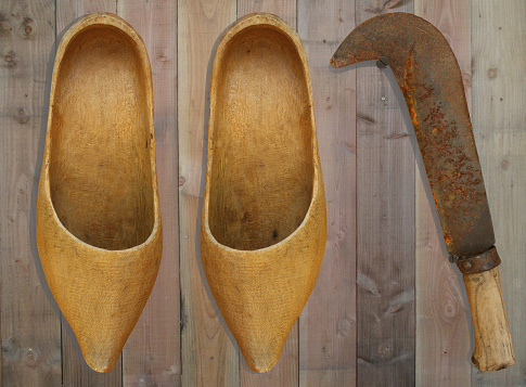 Wooden clogs and sickle hanging on a wooden facade
