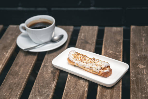 istock Cup of coffee and eclair on a wooden table close-up. 1404721309