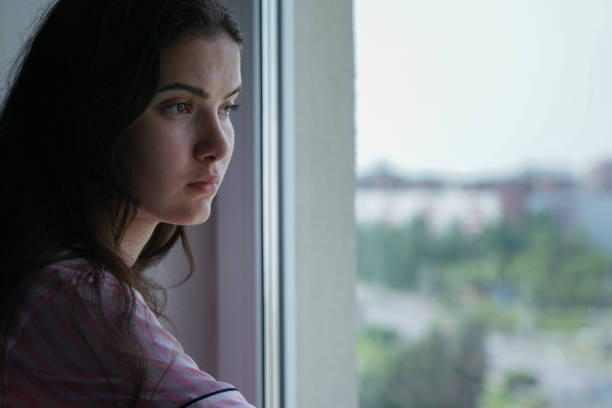 istock Sad young brunette looking through window glass side view 1404722128