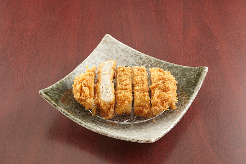 Tonkatsu served in a dish isolated on wooden table background side view of singapore food