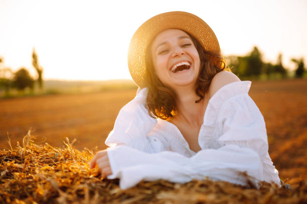 istock Happy woman near haystack at sunset. 1404727332