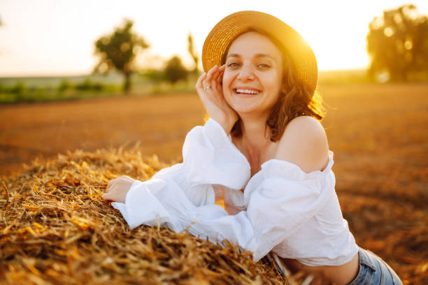 istock Happy woman near haystack at sunset. 1404727345