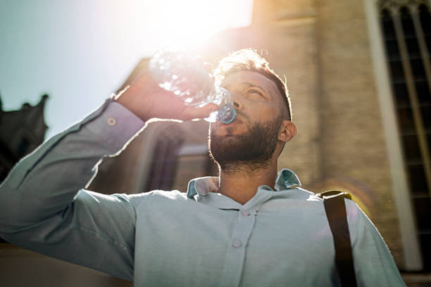 uomo d'affari sorridente idratante - drinking men water bottle foto e immagini stock