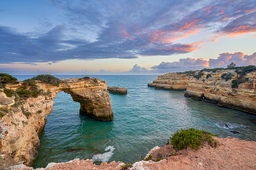 Sunset at Albandeira Arch at Praia de Albandeira's beautiful rocky coast and beach on the famous Algarve Coast in southern Portugal, Europe.